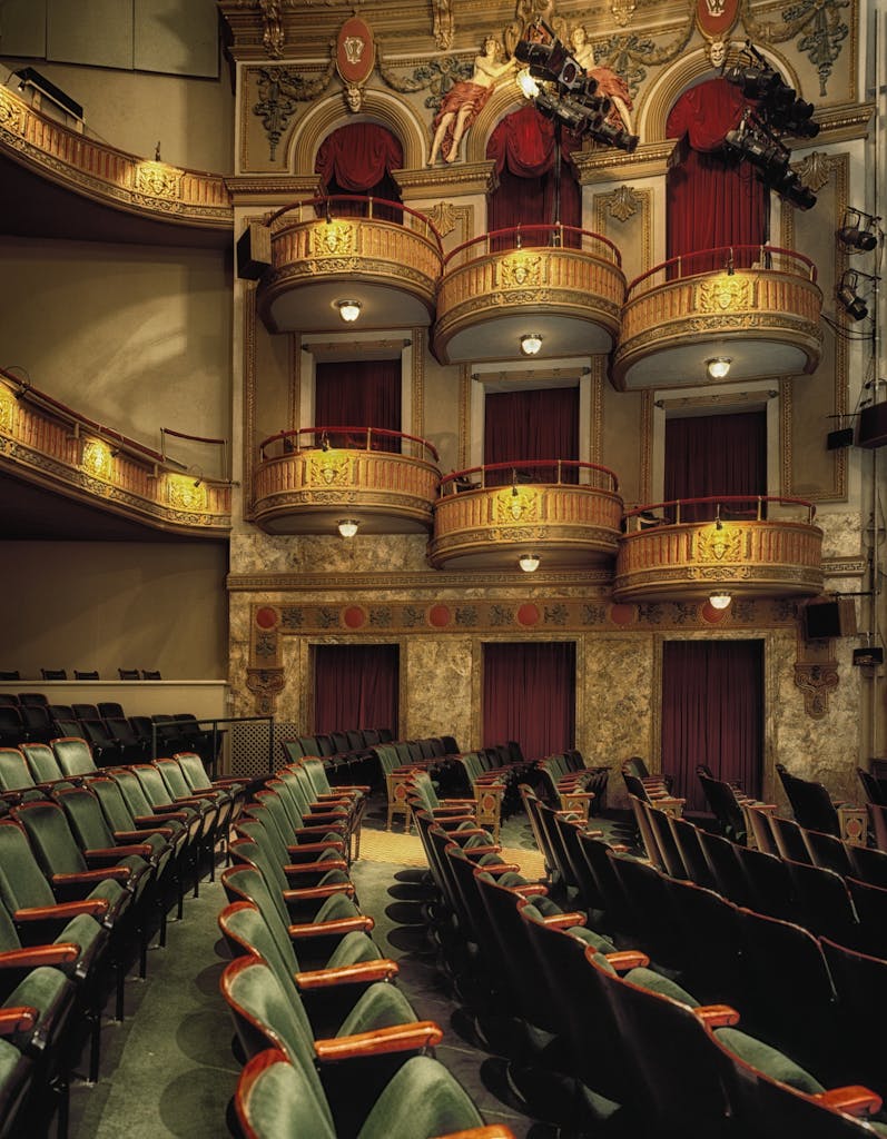 Classic theater interior featuring ornate balconies and empty seats, perfect for drama or performance themes.