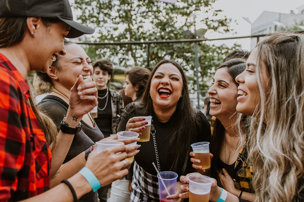 Group of young women laughing and enjoying drinks outdoors in São Paulo.